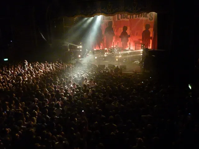 Crowded small club stage with guitars under red lights